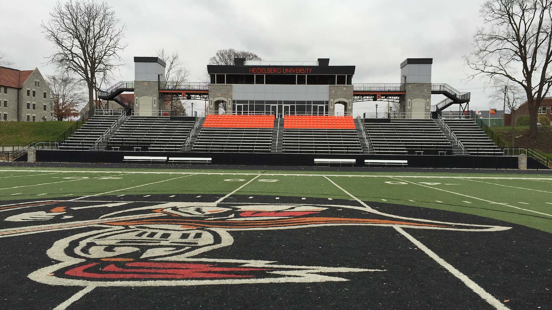 Heoremann Stadium grandstand features stadium seats with backs, aluminum bench seating, and a press box.