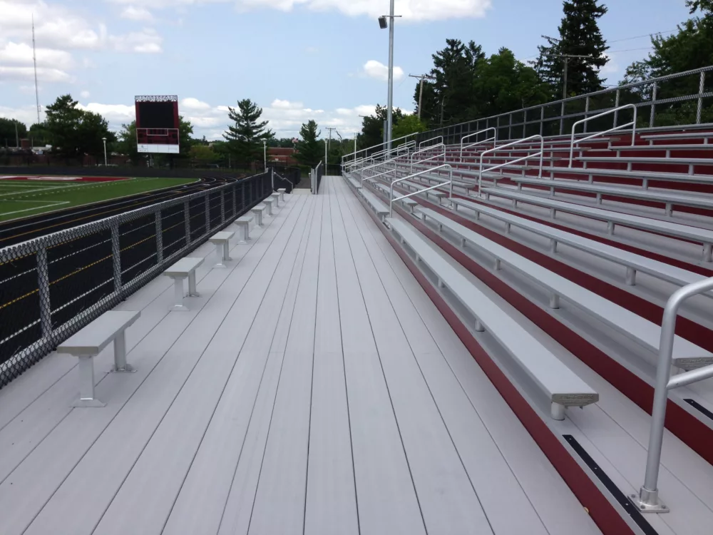 Alum-S-Stand bleacher with red risers and bench seating, featuring handicap ADA forward design